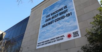 Banner on building reading The Vaccine is our Best Shot Against Covid-19