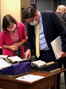 2 masked people look at rare manuscripts in a library