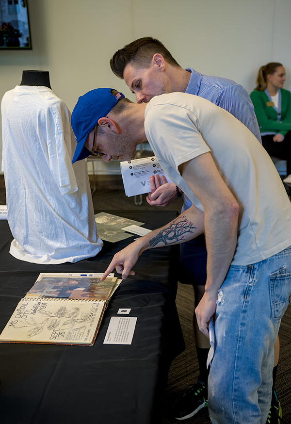 Attendees at a Special Collections and University Archives open house held in August view a 1990s-era scrapbook, part of the Heard Libraries’ Tina Louise Hummer Papers. (Tim Gollins/Vanderbilt)