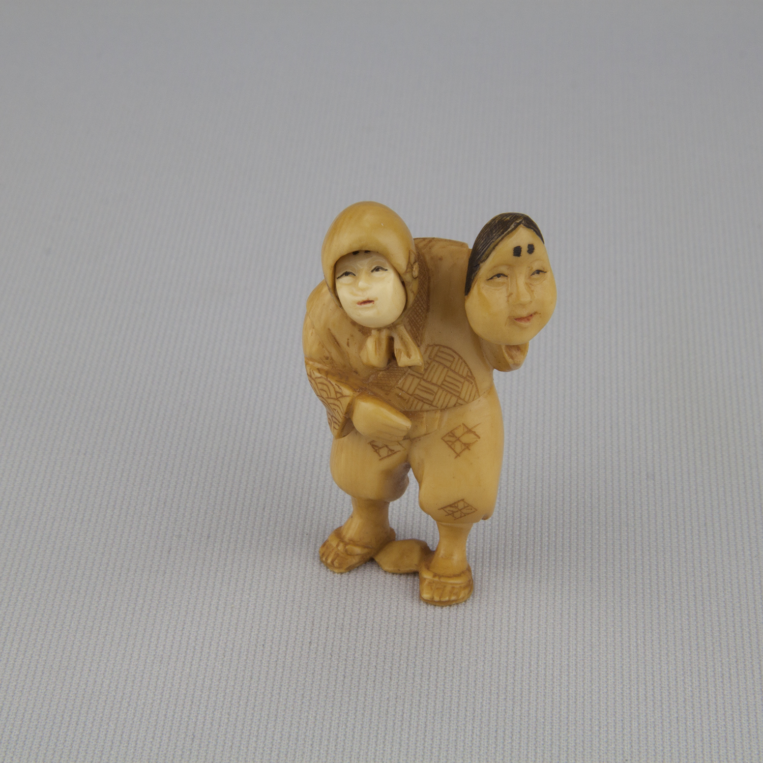 Netsuke depicting standing man with rotating face, holding an Okame mask, ca. 18th–19th century, ivory, The Herman D. Doochin Collection, 1992.168